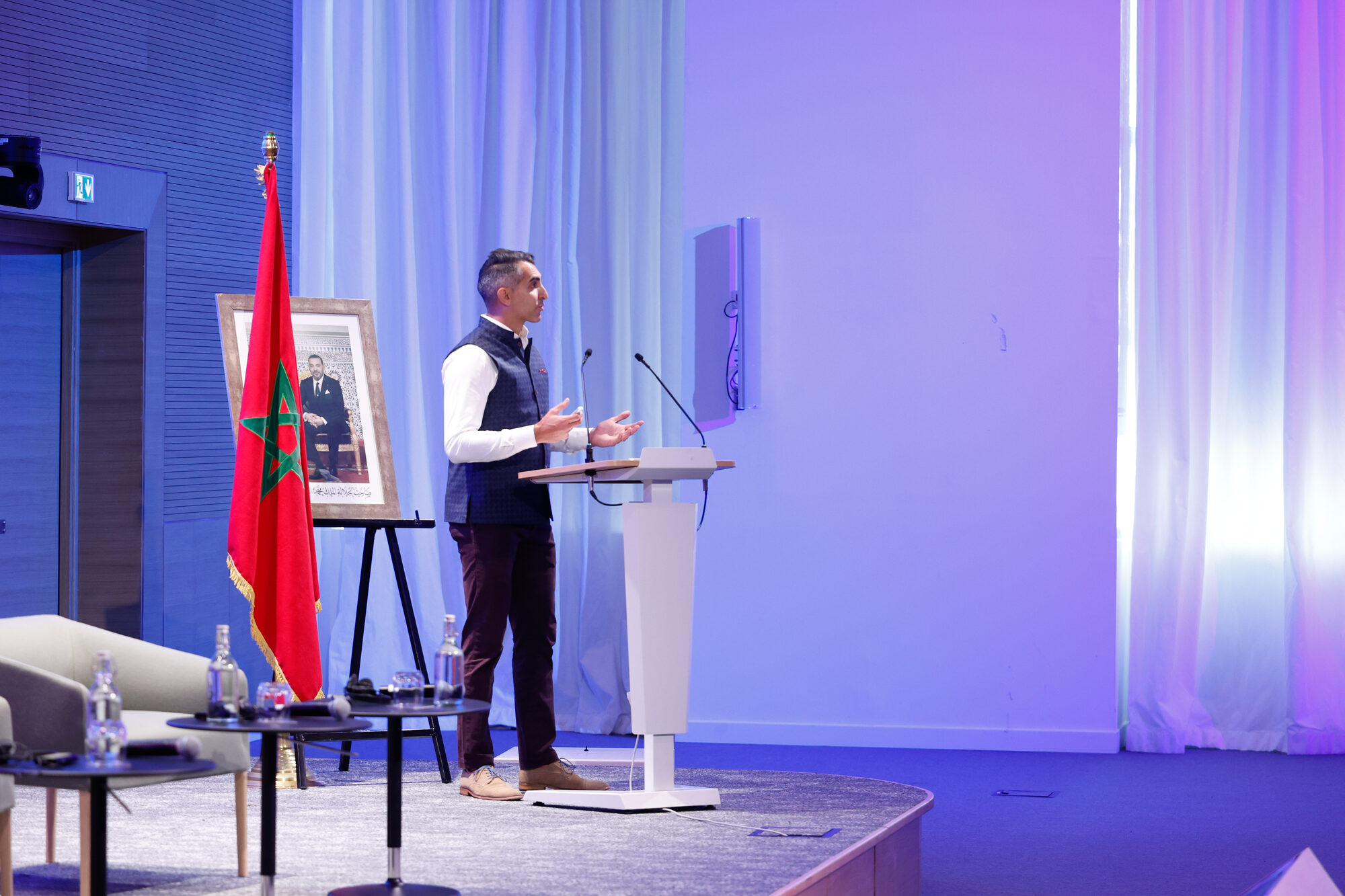 A speaker on stage under stage lighting